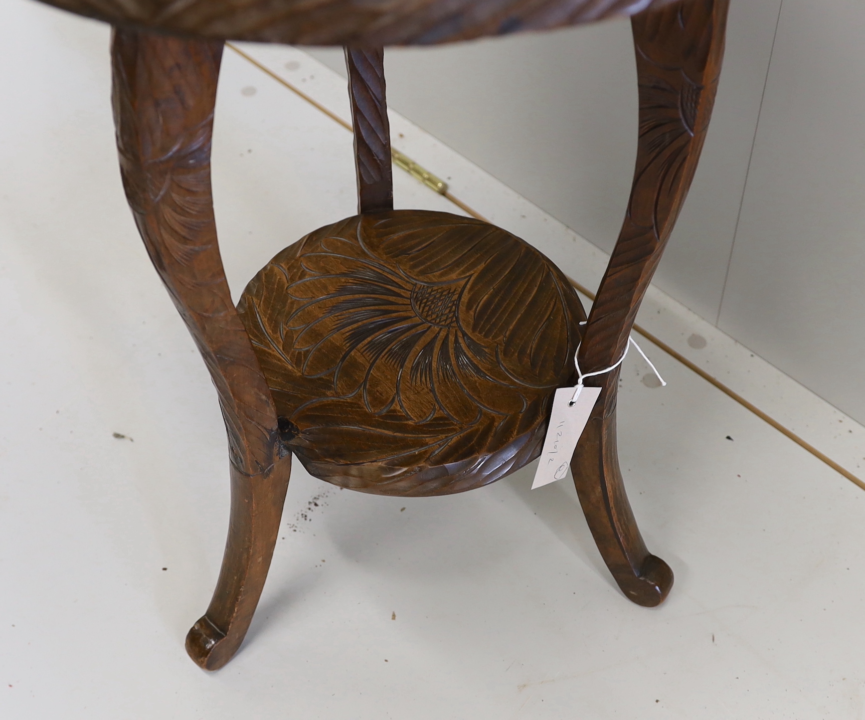 An early 20th century Liberty style carved two tier occasional table, diameter 44cm, height 61cm
